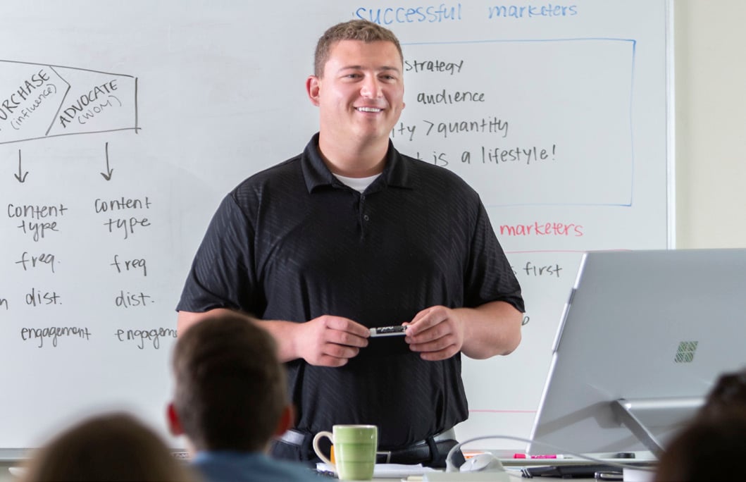 A smiling person teaching a class